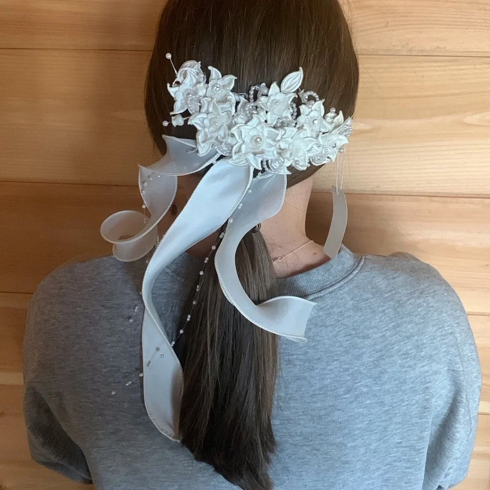 White floral and satin ribbon hairpiece with pearl and rhinestone detail